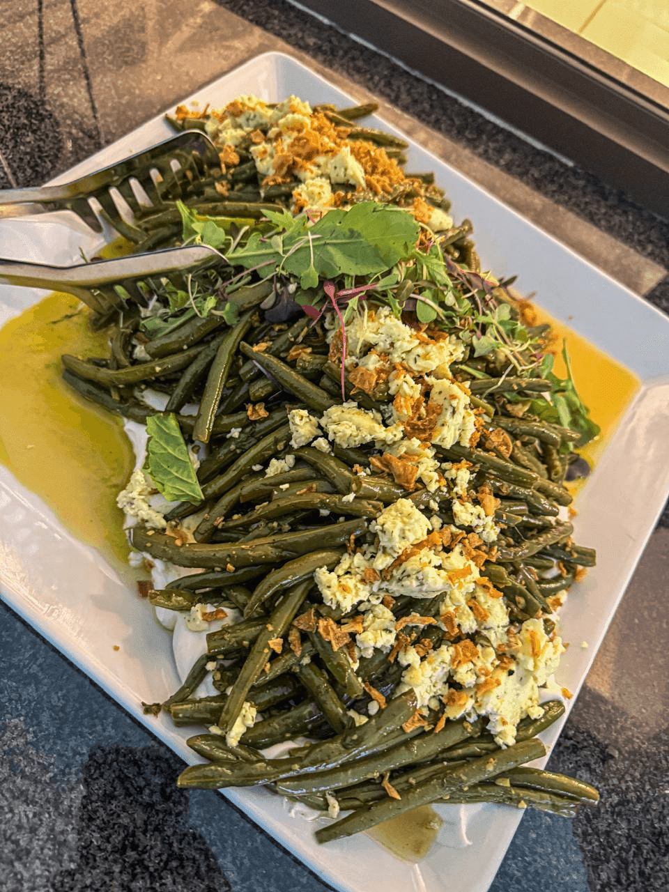 Sautéed green bean and basil pesto salad, plated long.