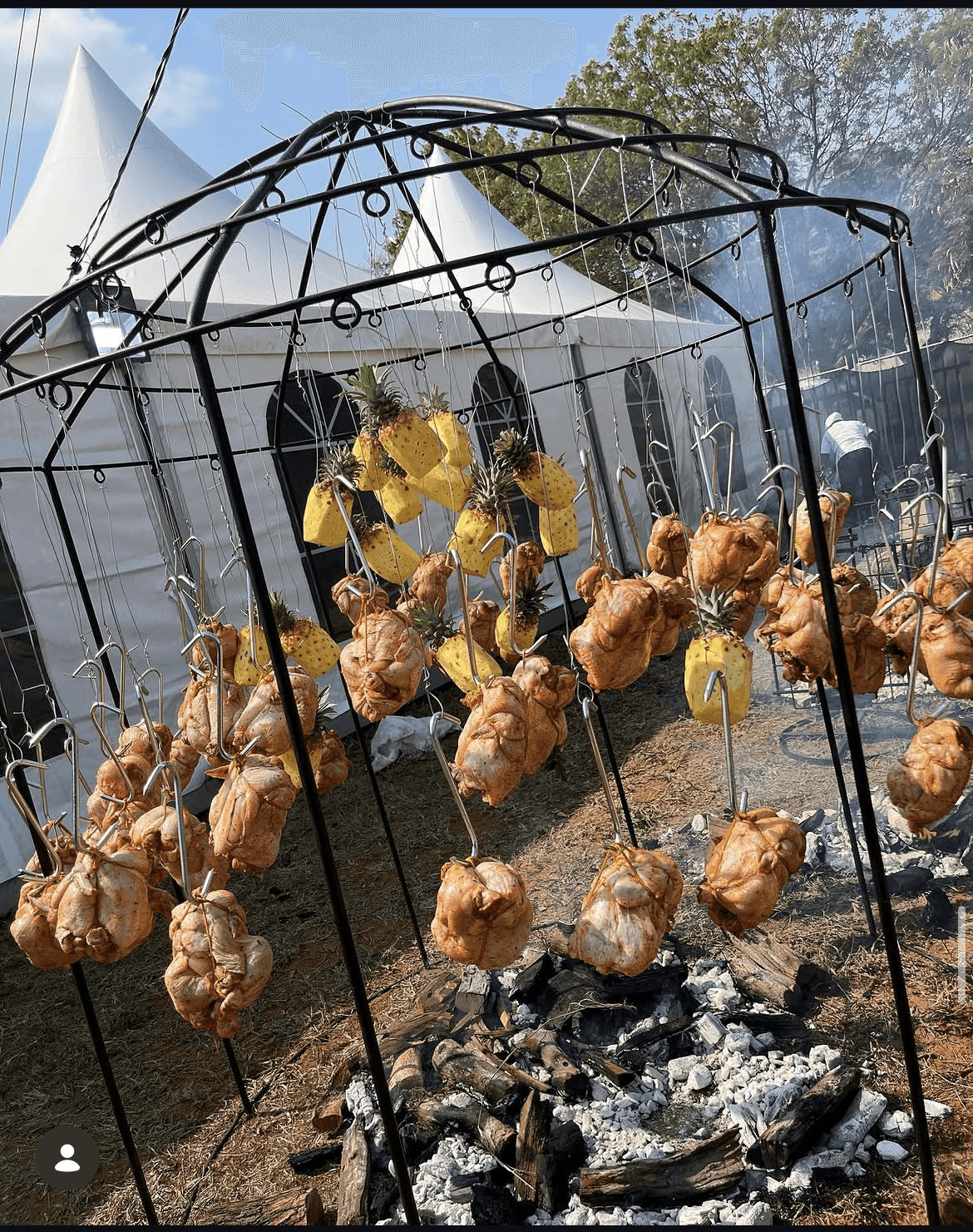 Dozens of whole chickens hanging over open coals at a barbecue festival.