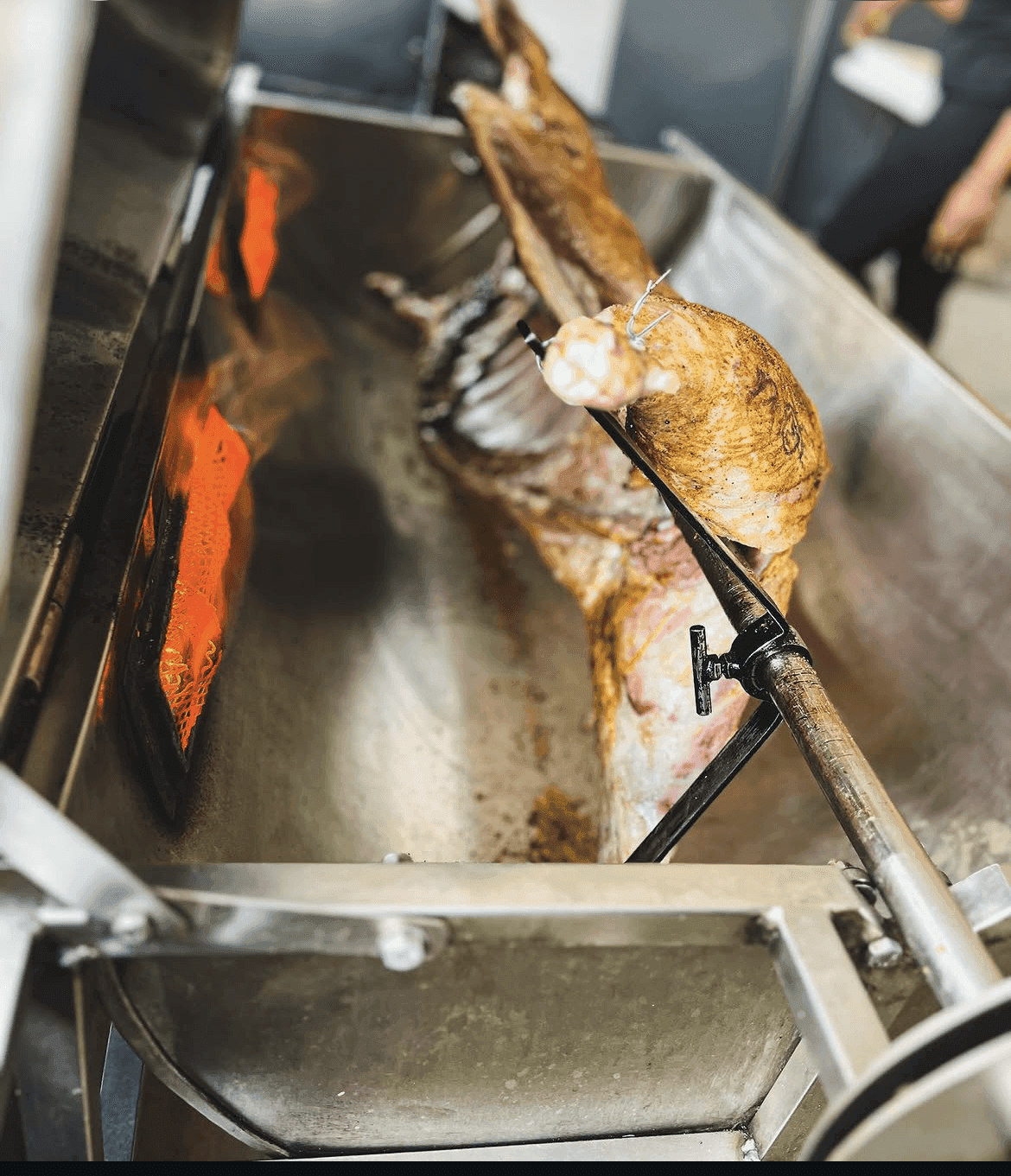 A whole lamb roasting on the spit with open flame, cooked on site.